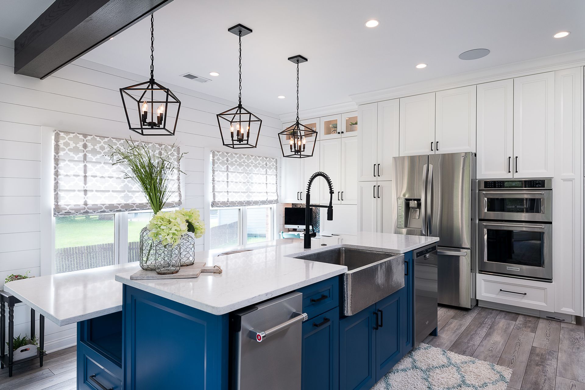 A kitchen with blue cabinets , stainless steel appliances , and a large island.