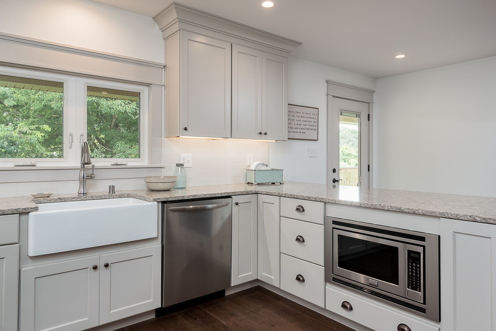 A kitchen with white cabinets , granite counter tops , stainless steel appliances and a sink.