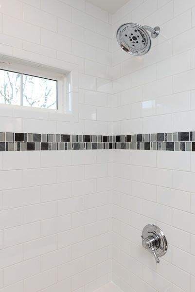 A shower with a black and white tile border and a window.