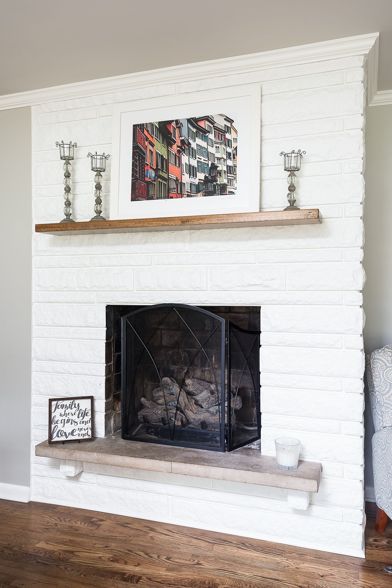 A white brick fireplace with a wooden mantle in a living room.