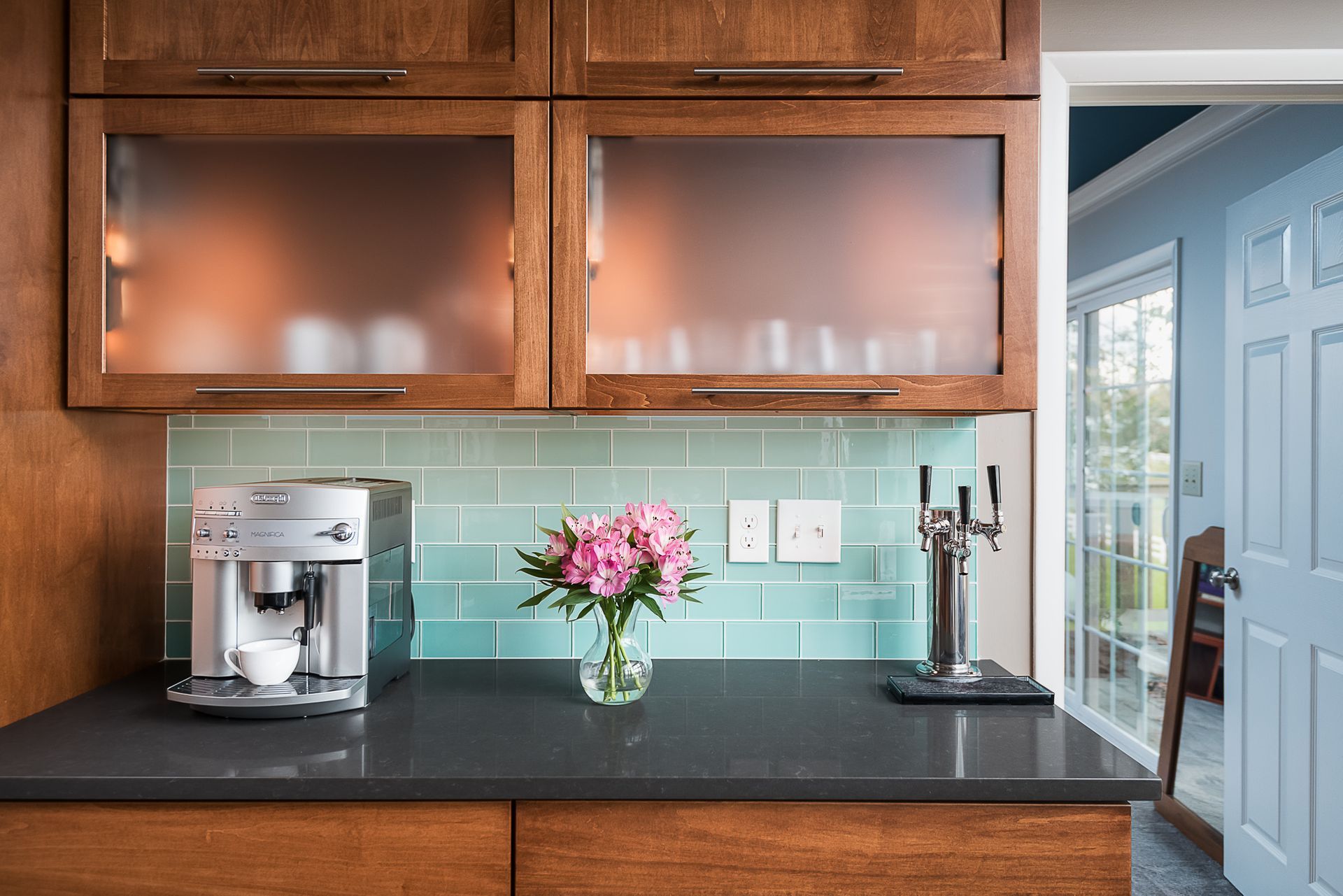 A kitchen with a coffee maker and a vase of flowers on the counter.