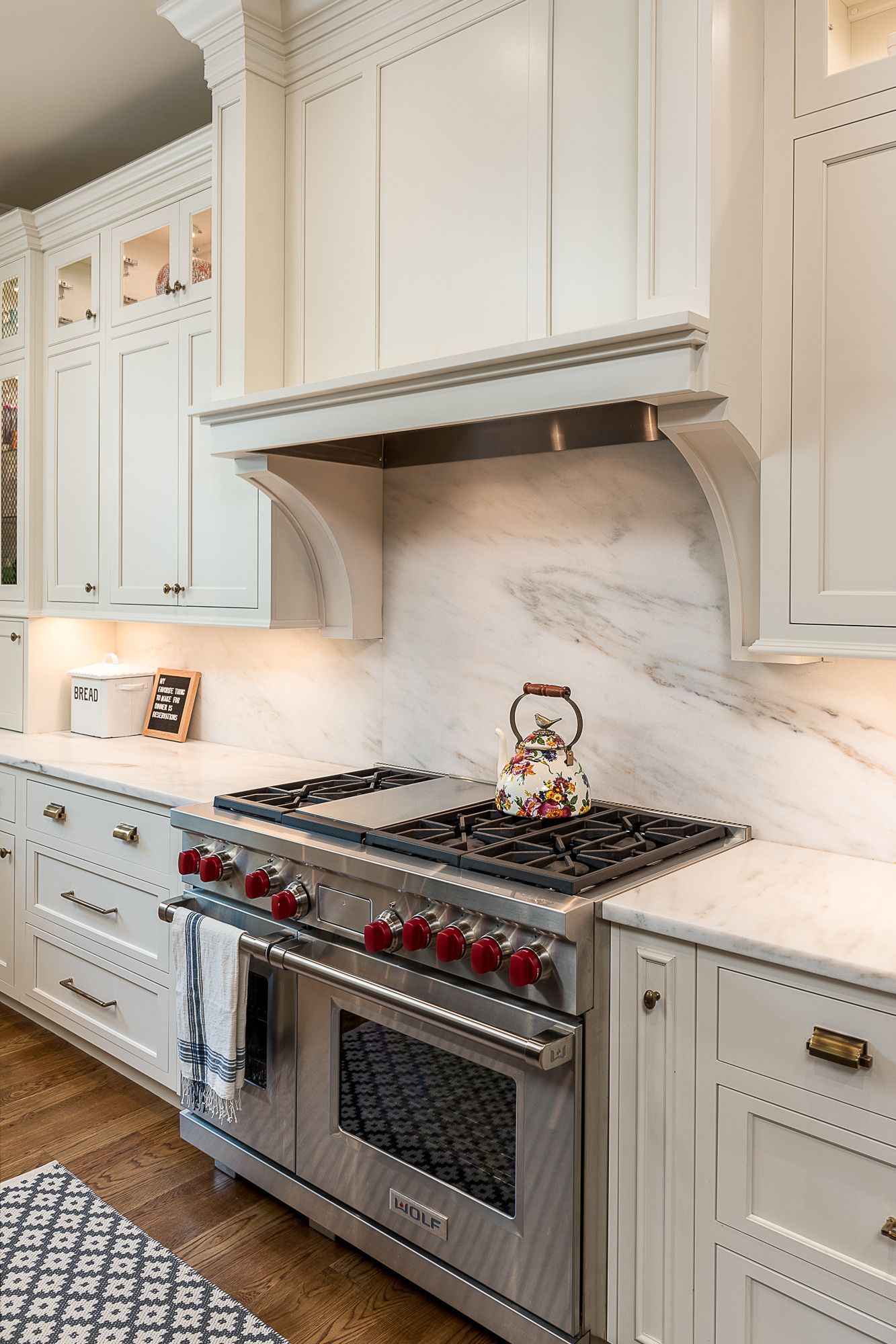 A kitchen with white cabinets and a stove top oven.