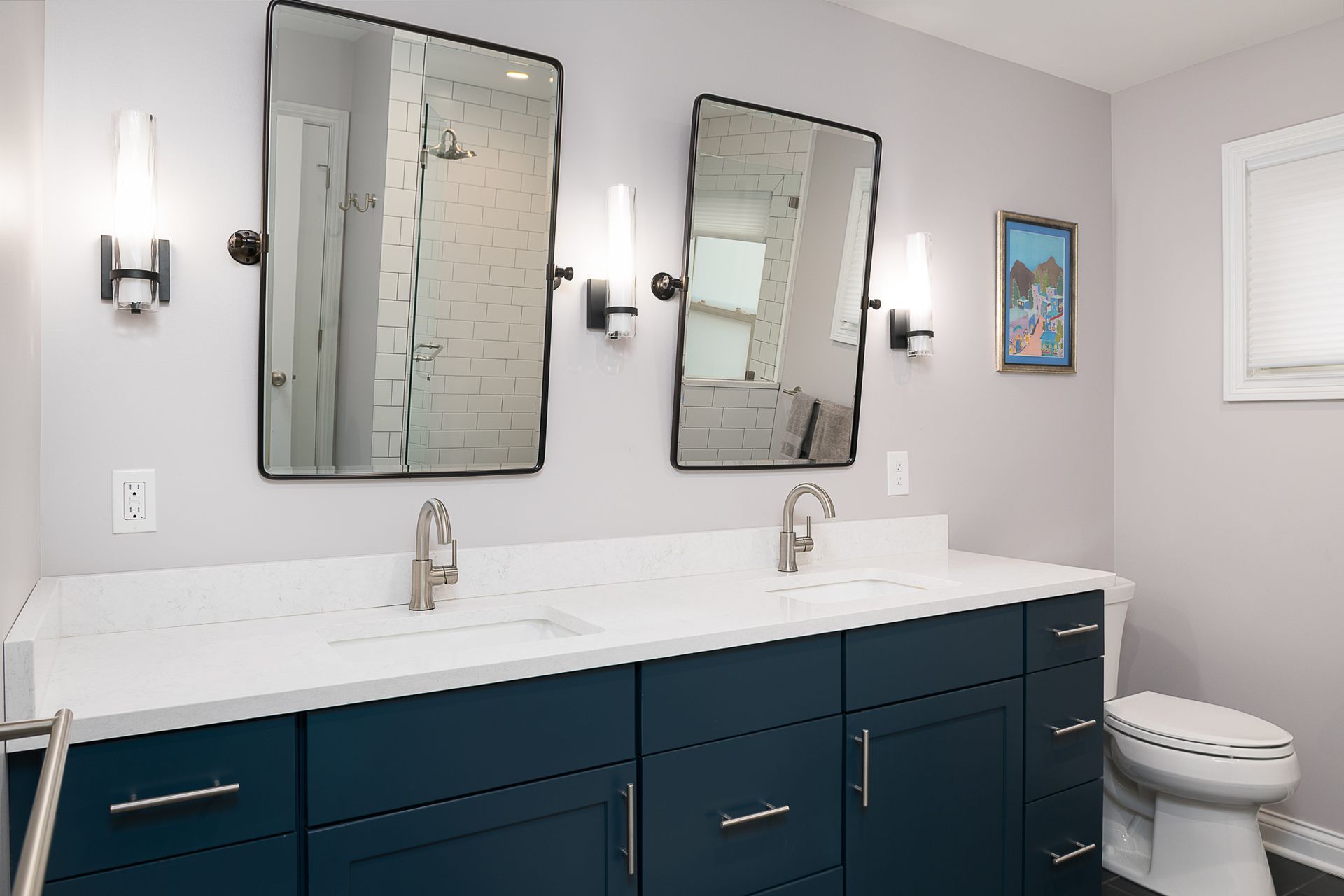 A bathroom with two sinks , two mirrors and a toilet.