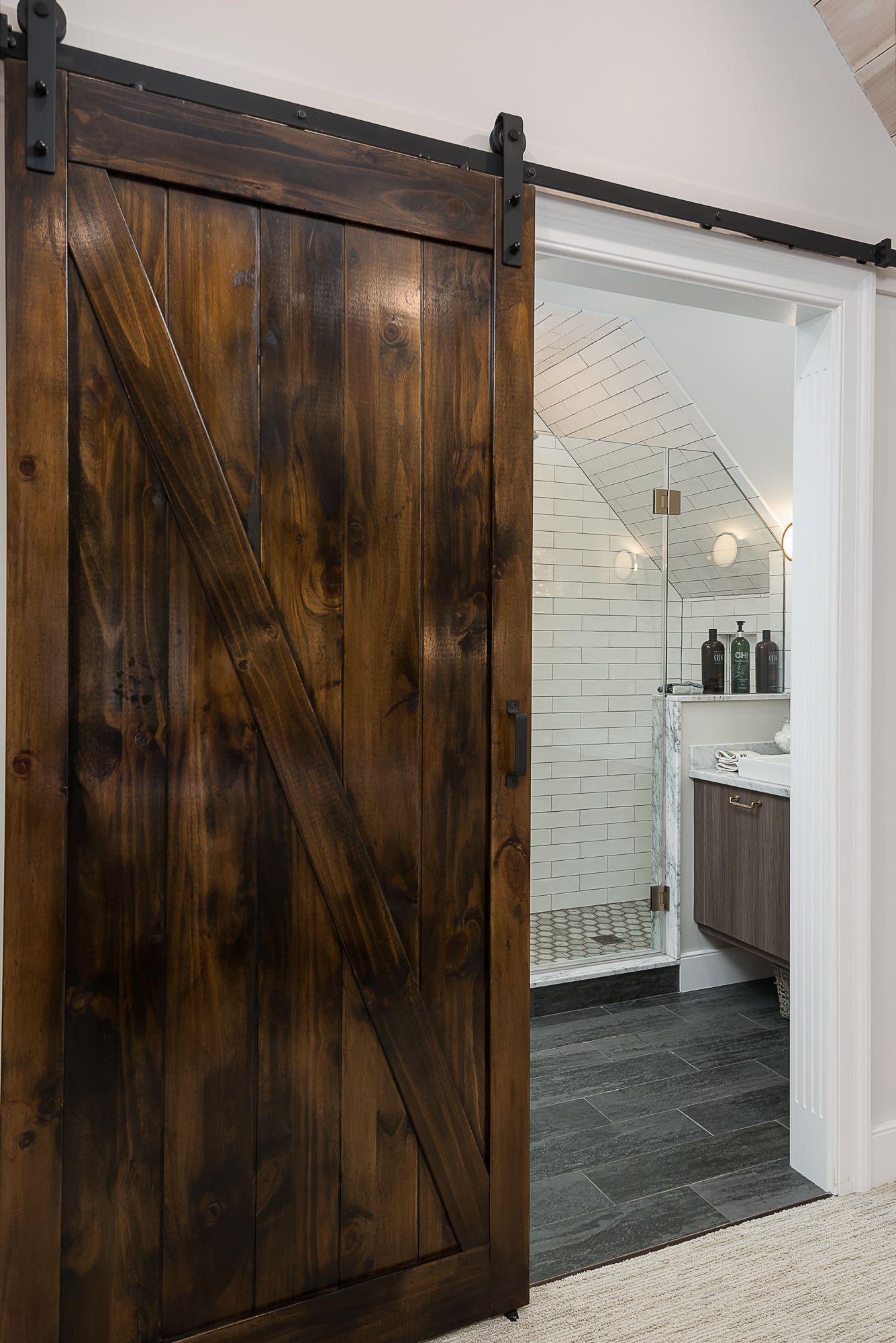 A wooden sliding barn door is open to a bathroom.