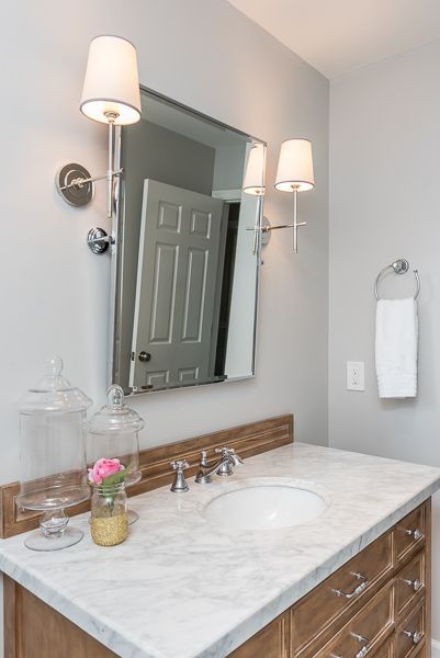 A bathroom with a sink , mirror , and light fixtures.