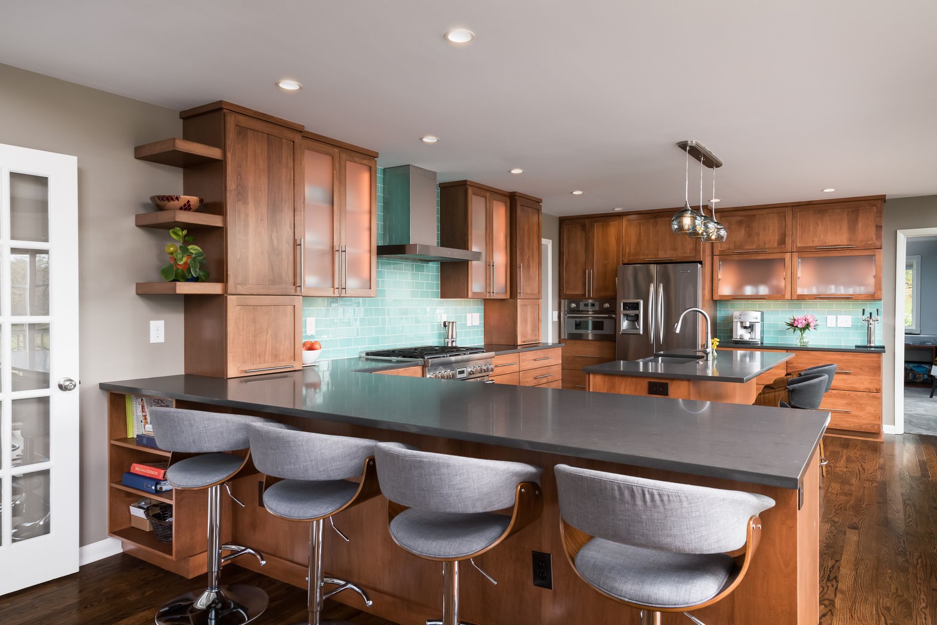 A kitchen with a large island , stools and a refrigerator.