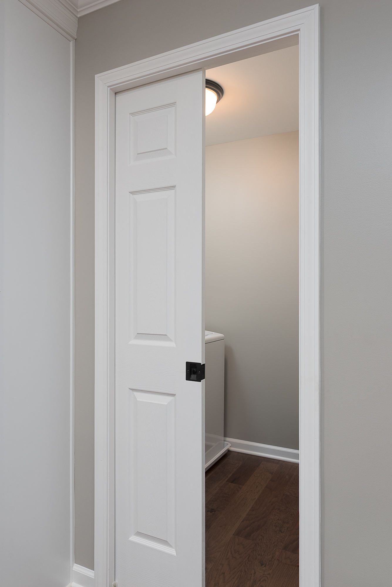 A white sliding door is open to a laundry room.