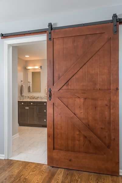 A wooden sliding barn door is open to a bathroom.