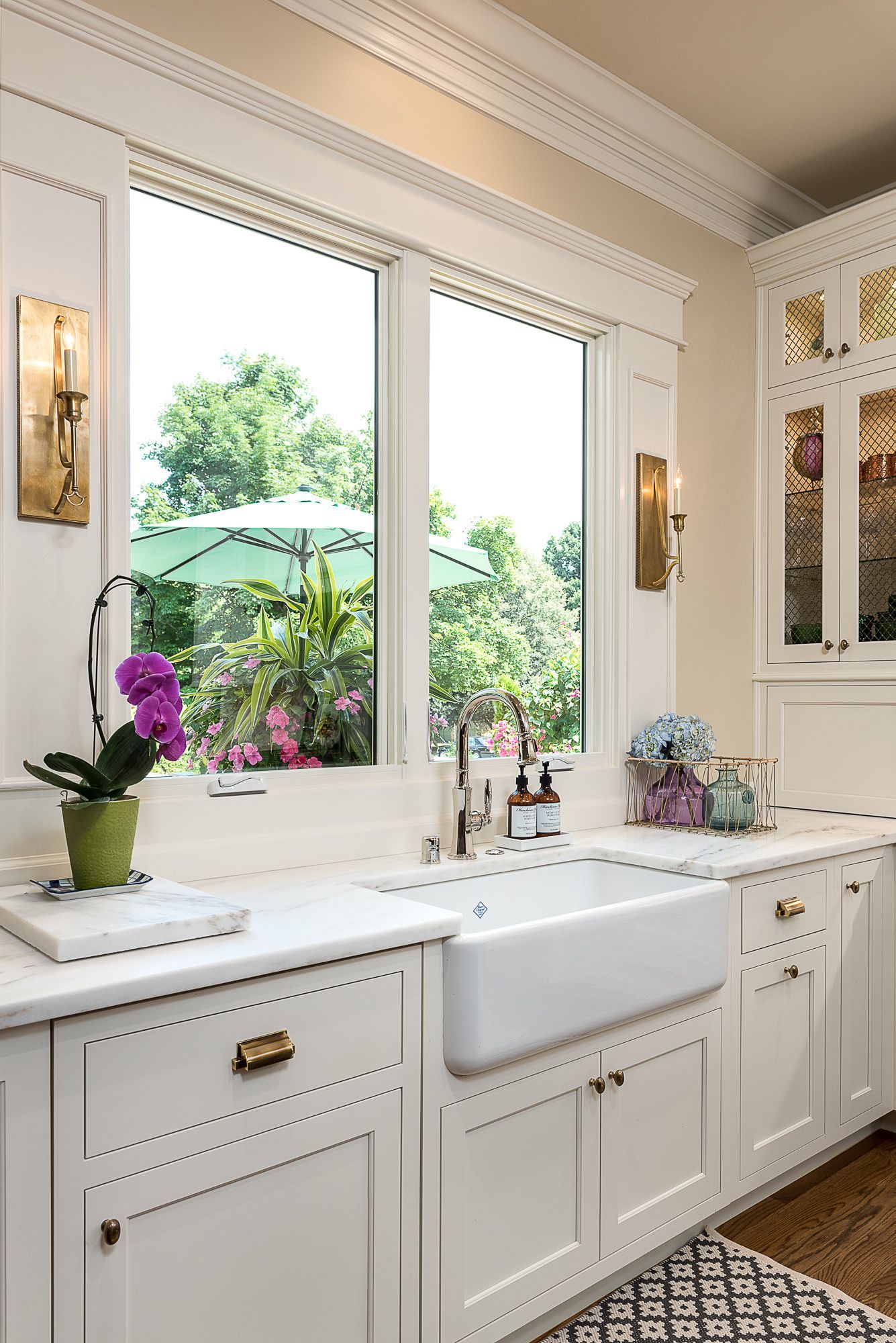 A kitchen with a sink , cabinets , and a large window.