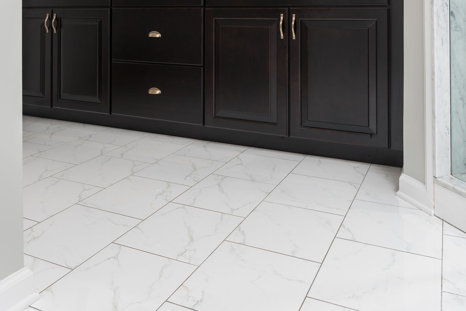 A bathroom with black cabinets and white tile floors.