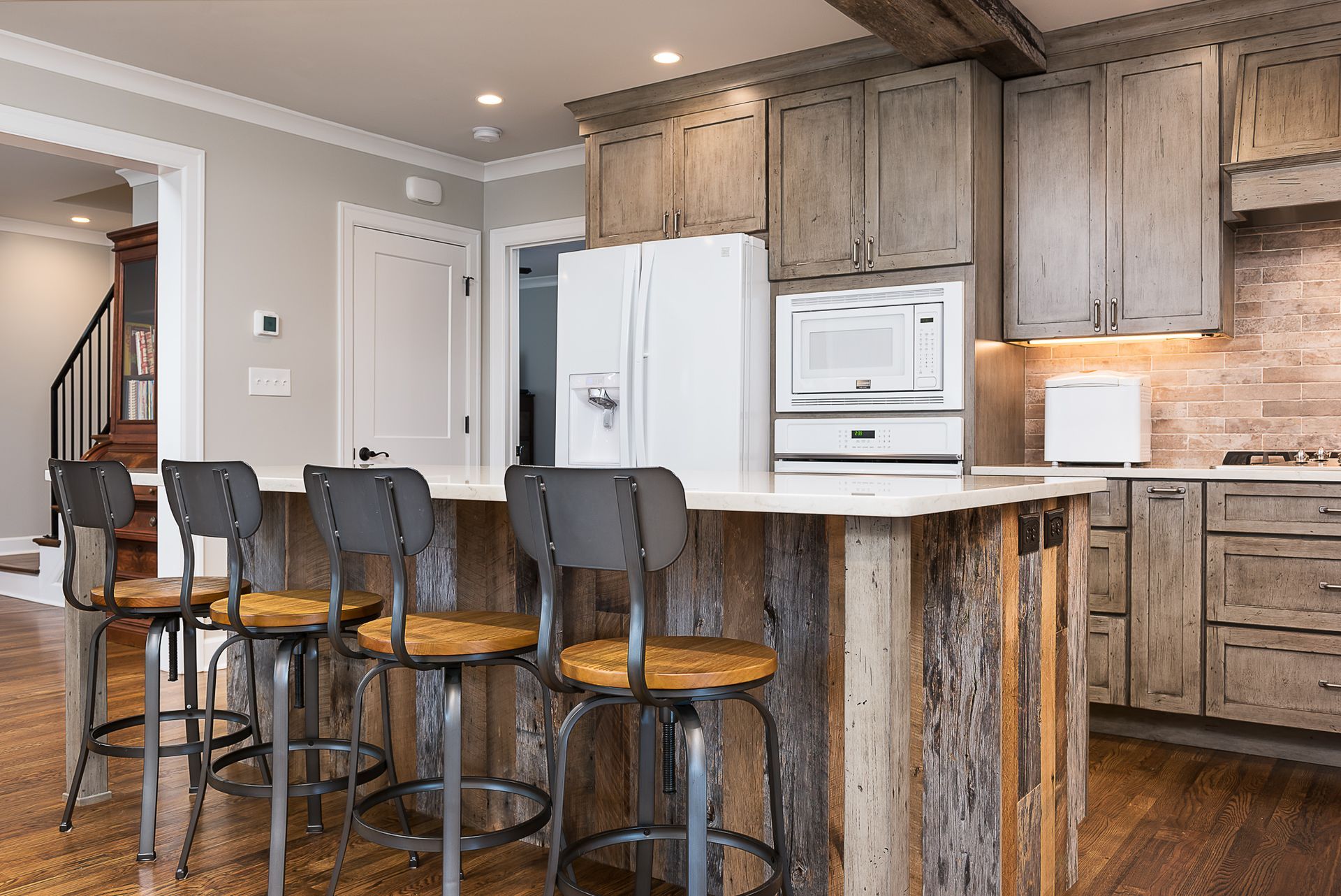 A kitchen with wooden cabinets and stools and a large island.