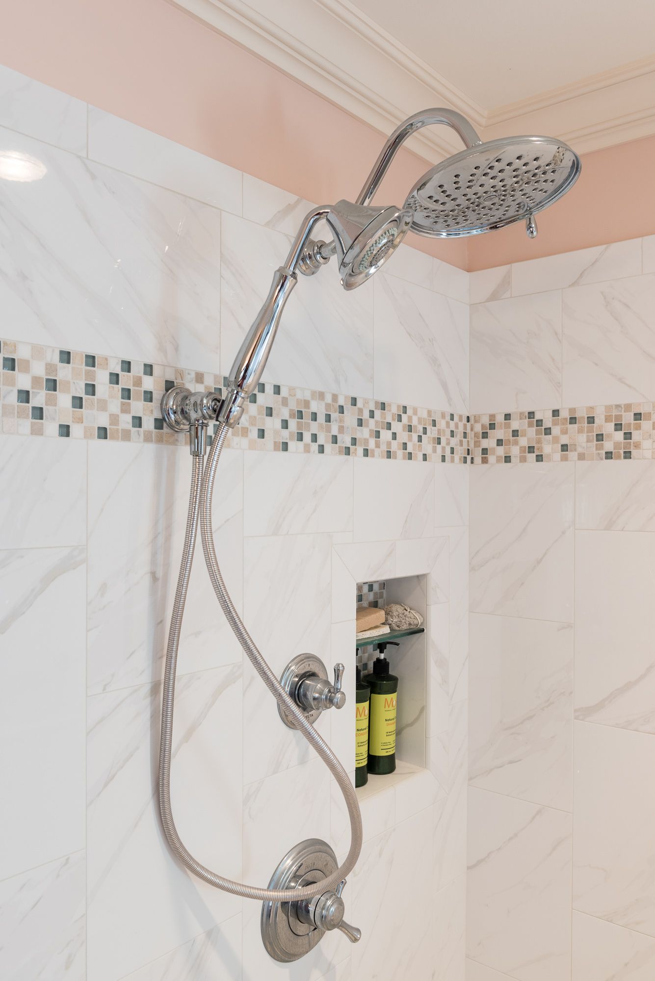 A shower head is hanging from the ceiling in a bathroom.