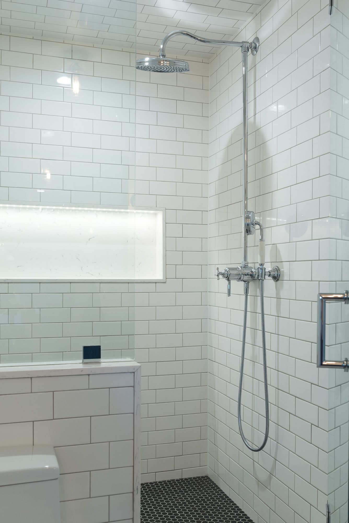 A bathroom with white tiles and a shower head