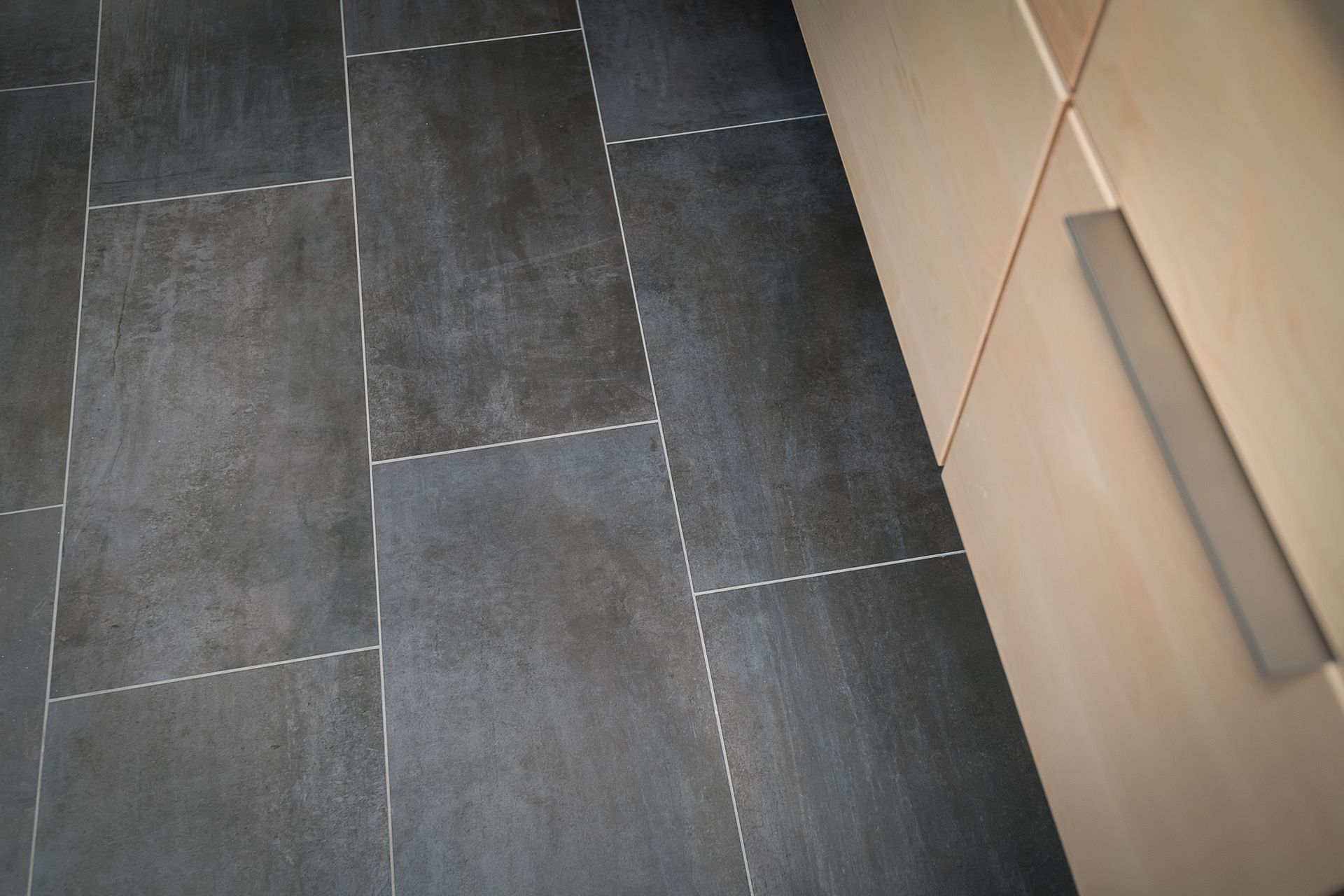 A black tile floor next to a white cabinet