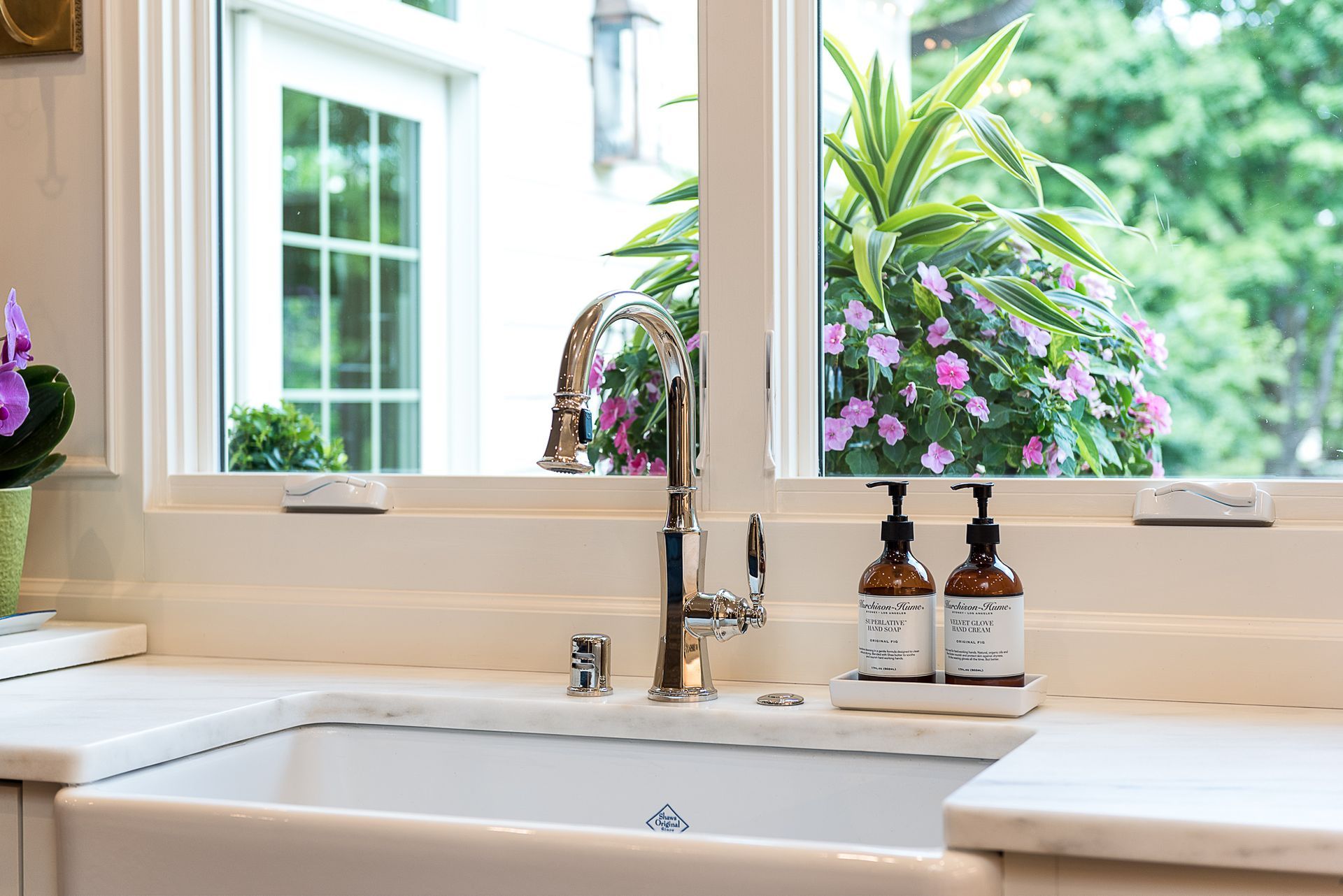 A kitchen sink with two soap dispensers under a window.