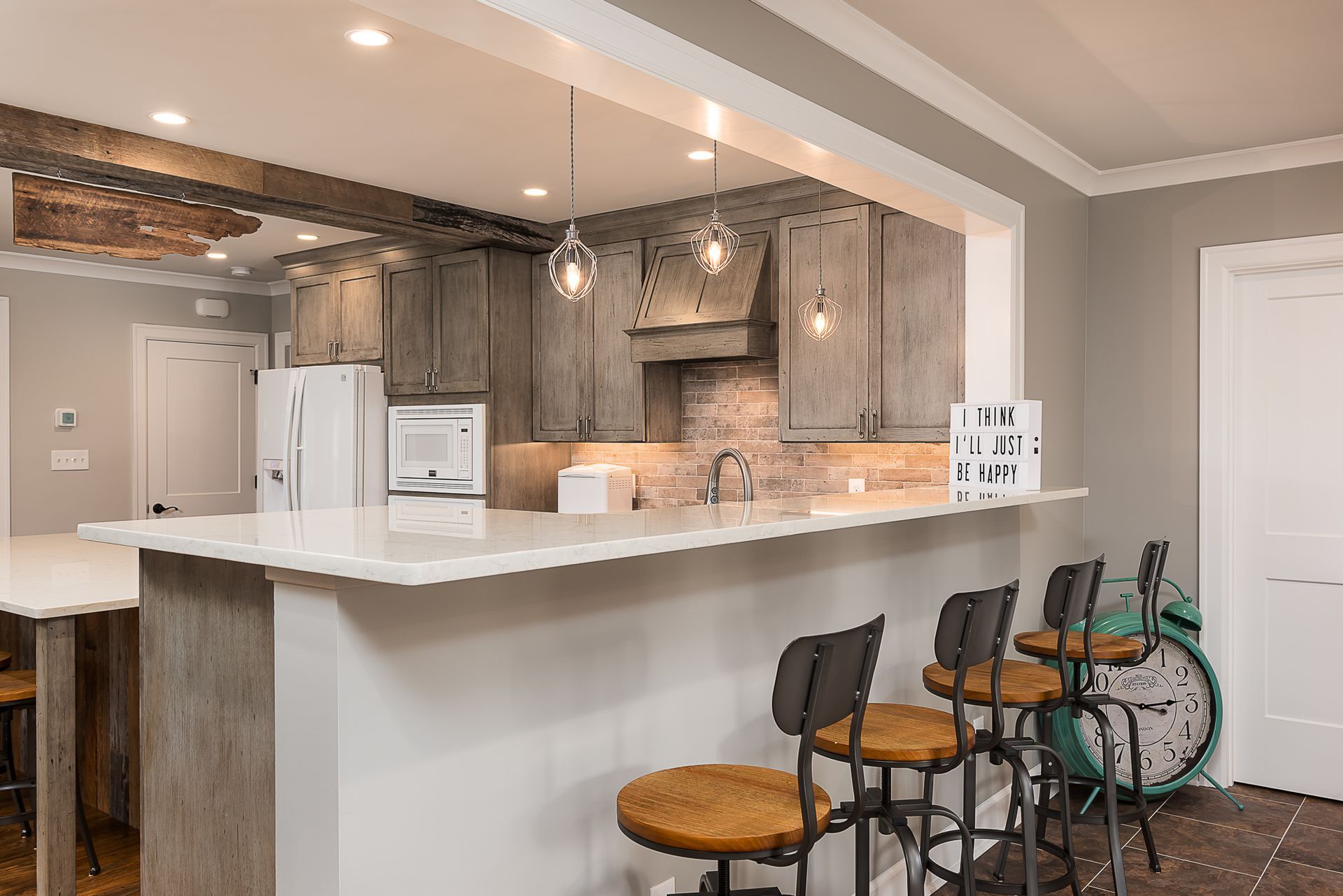 A kitchen with a long counter and stools and a clock on the wall.