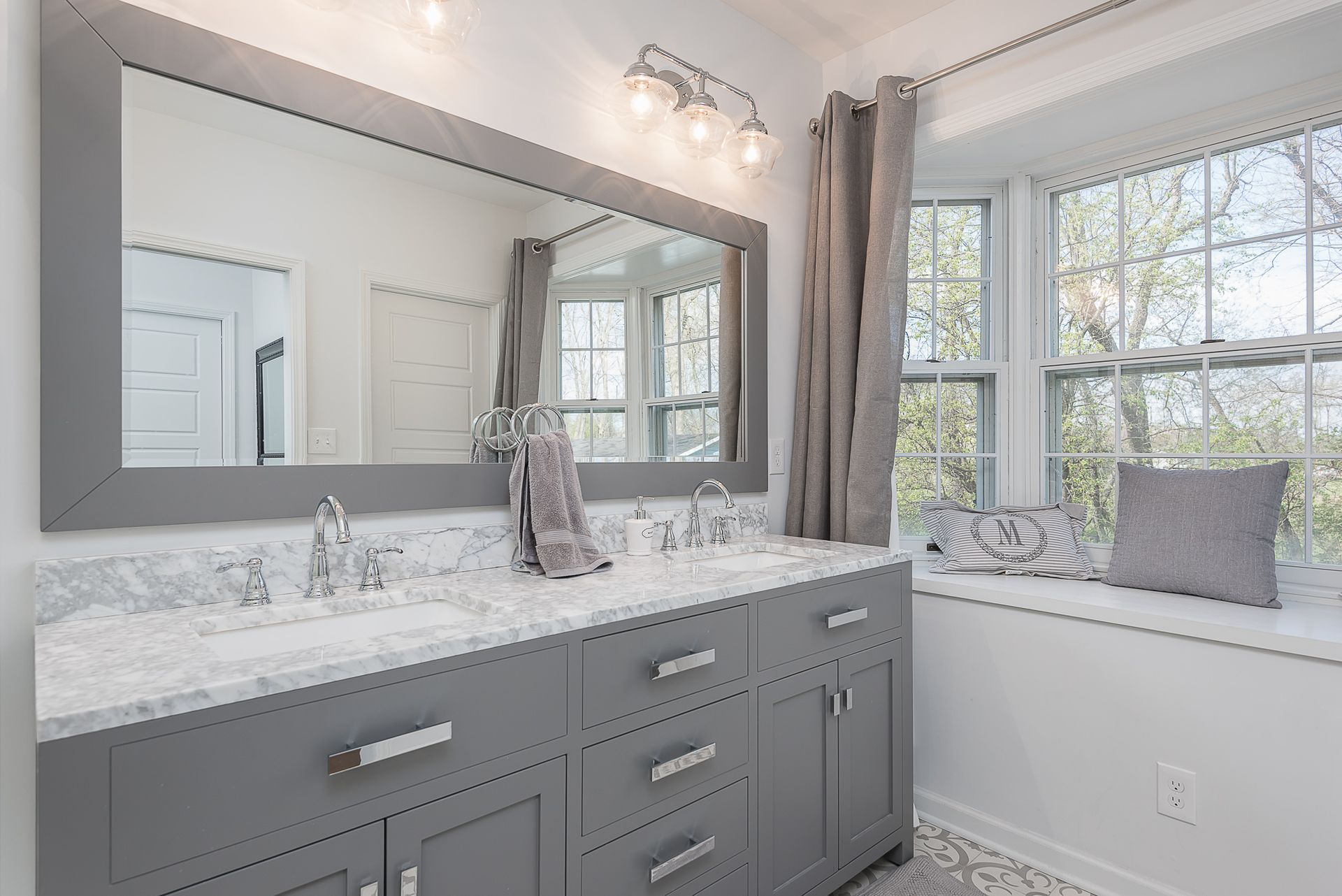A bathroom with two sinks , a large mirror and a window seat.