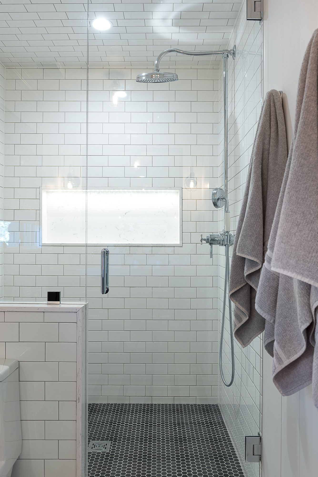 A bathroom with white tiles and a walk in shower.