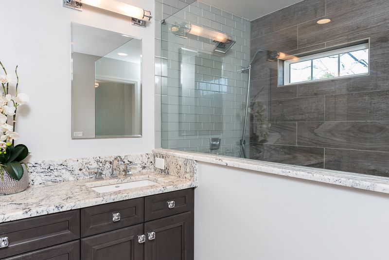 A bathroom with a sink , mirror , and walk in shower.