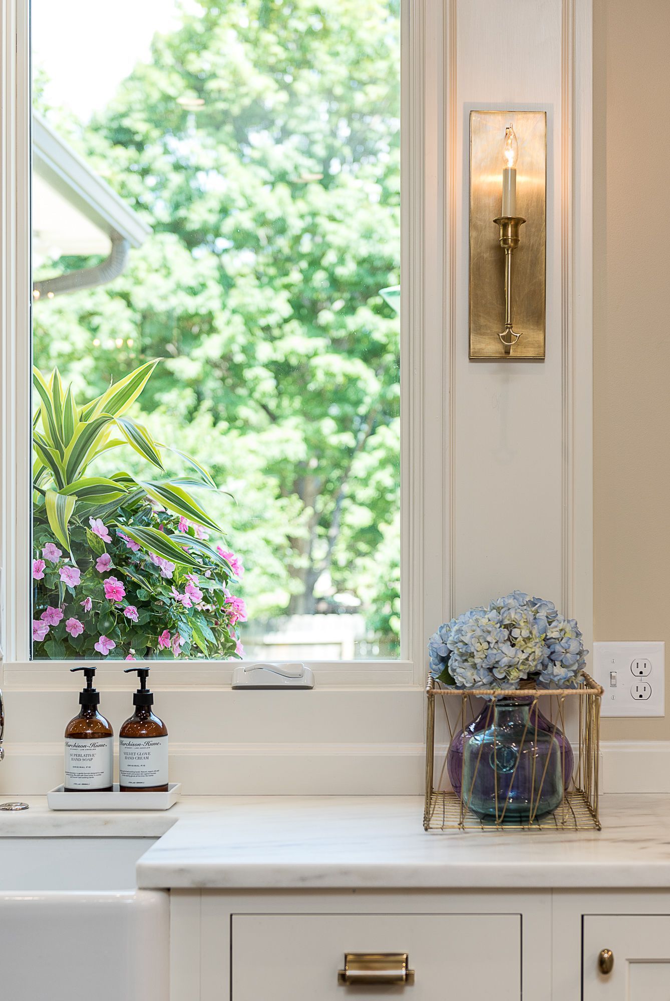 A kitchen with a sink and a window with flowers in the window.