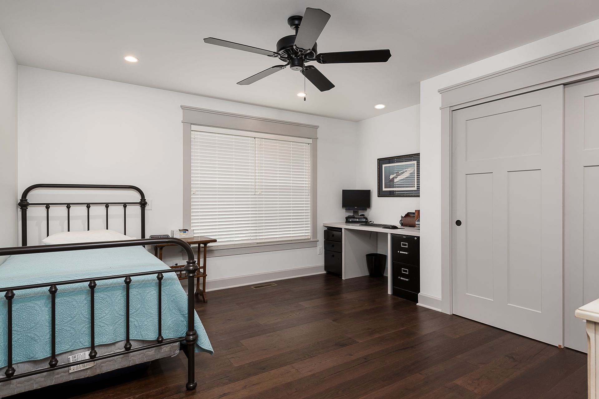 A bedroom with a bed , desk and ceiling fan.