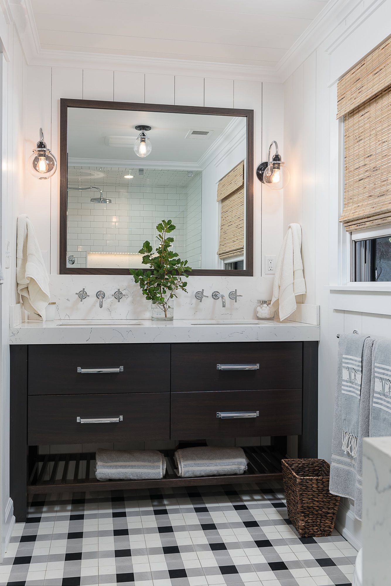 A bathroom with a black and white checkered floor and a large mirror.