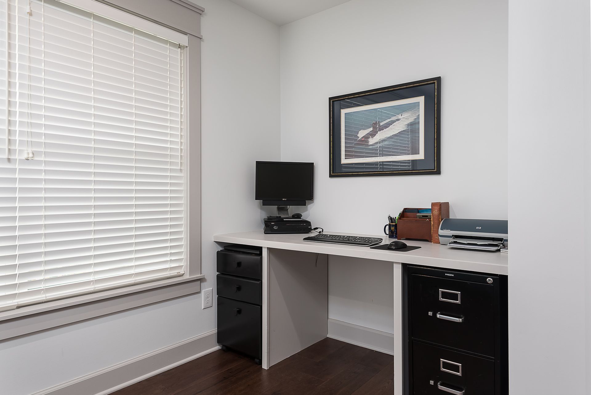 A room with a desk and a picture on the wall