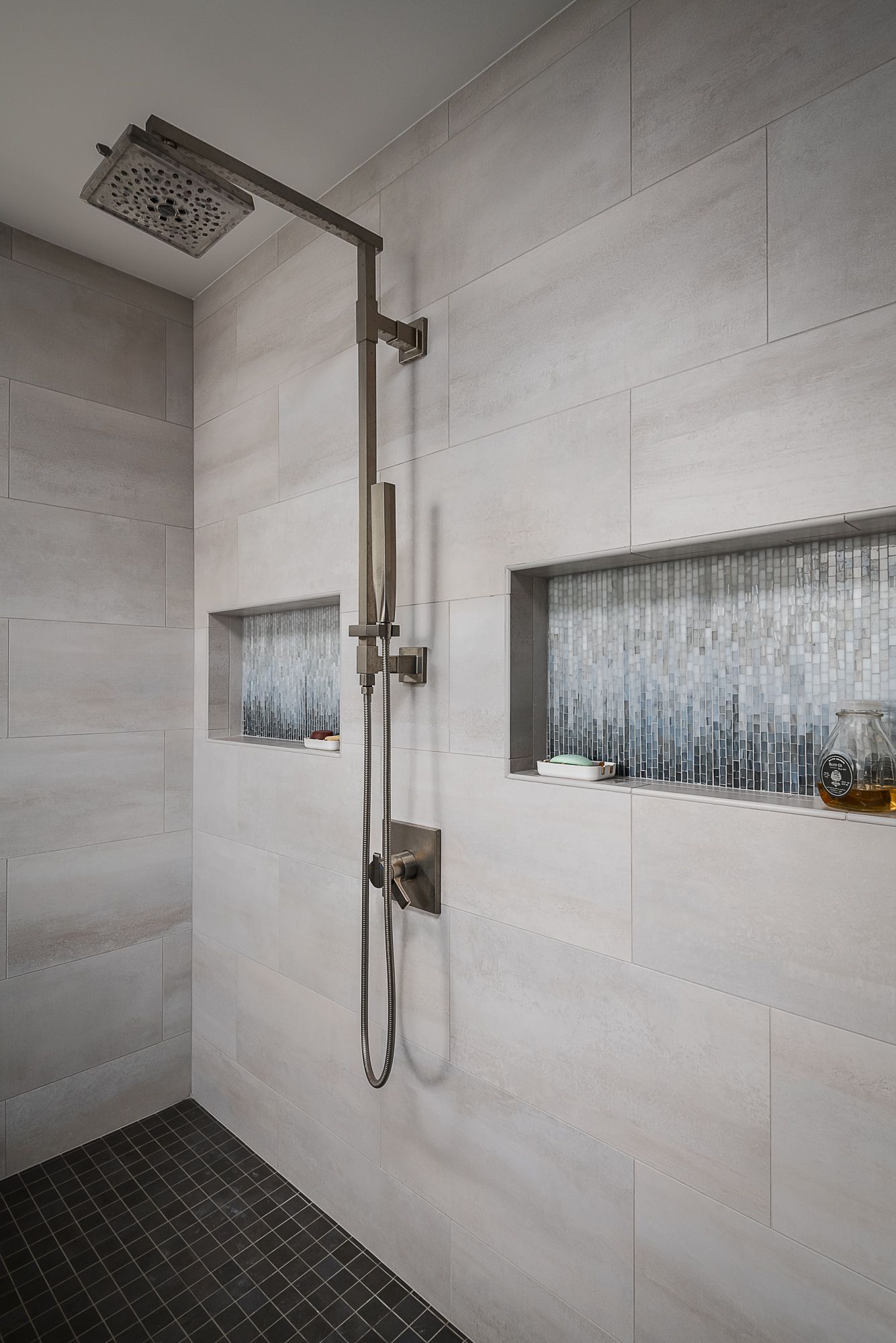 A shower with a shower head and a soap dish on the wall.