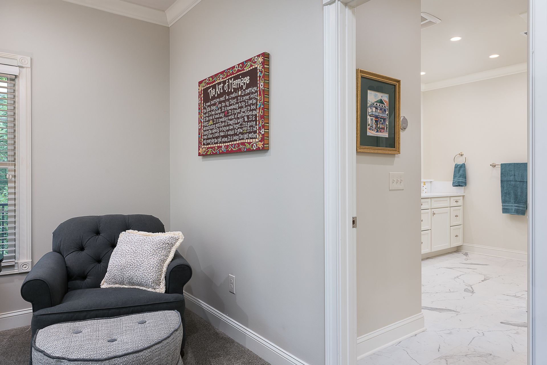 A chair and ottoman are in a room next to a bathroom.