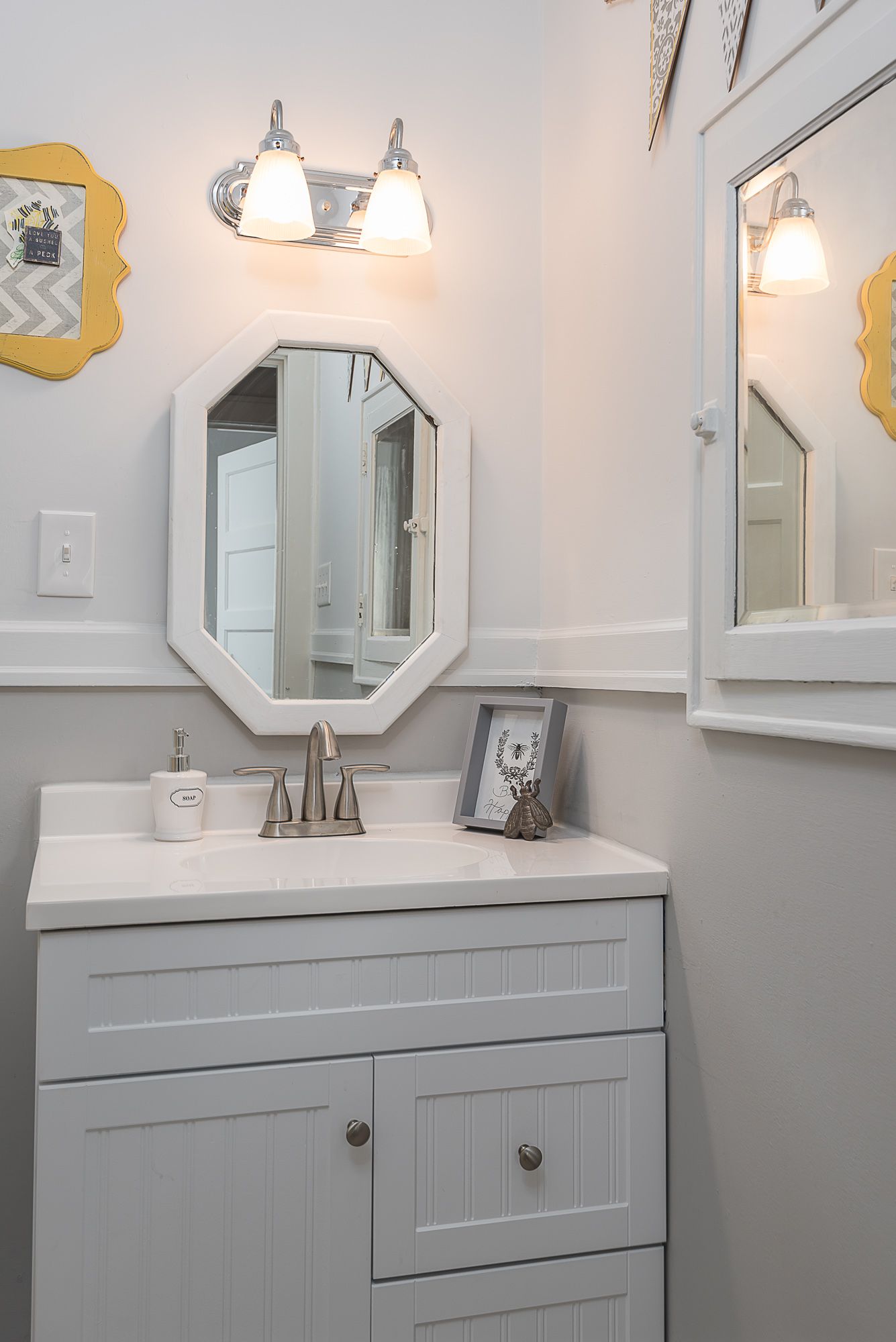 A bathroom with a sink , mirror and light.