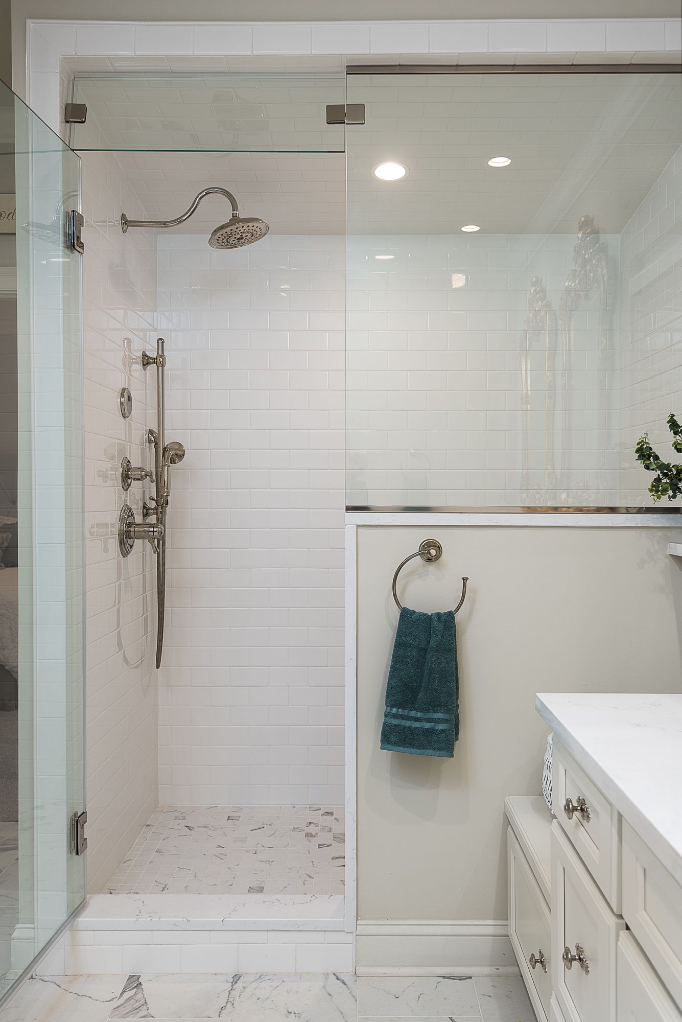 A bathroom with a walk in shower and a towel hanging on the wall.