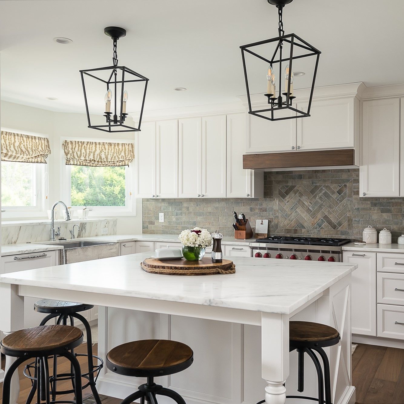 A kitchen with white cabinets and a large island with stools