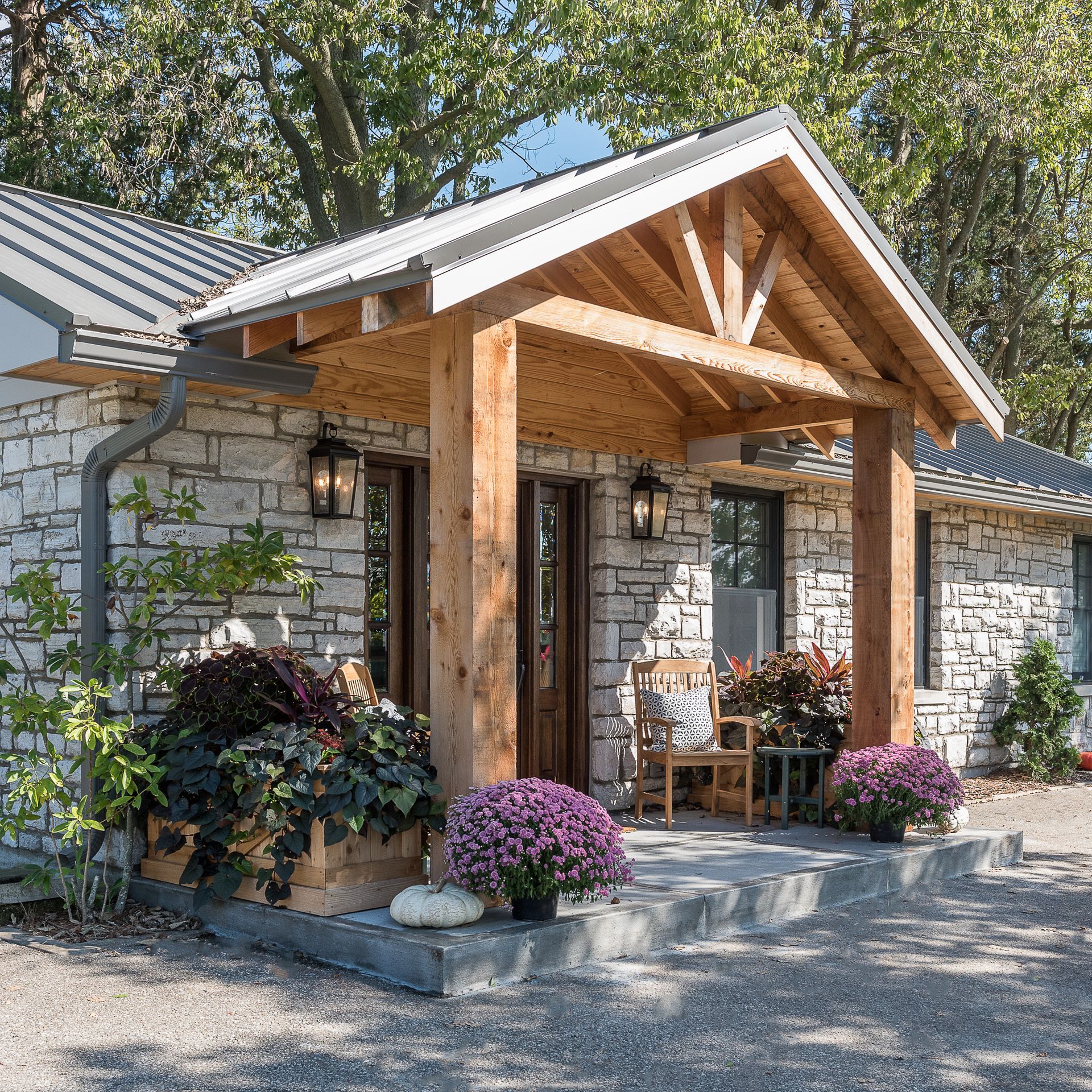 A stone house with a wooden porch and flowers in front of it