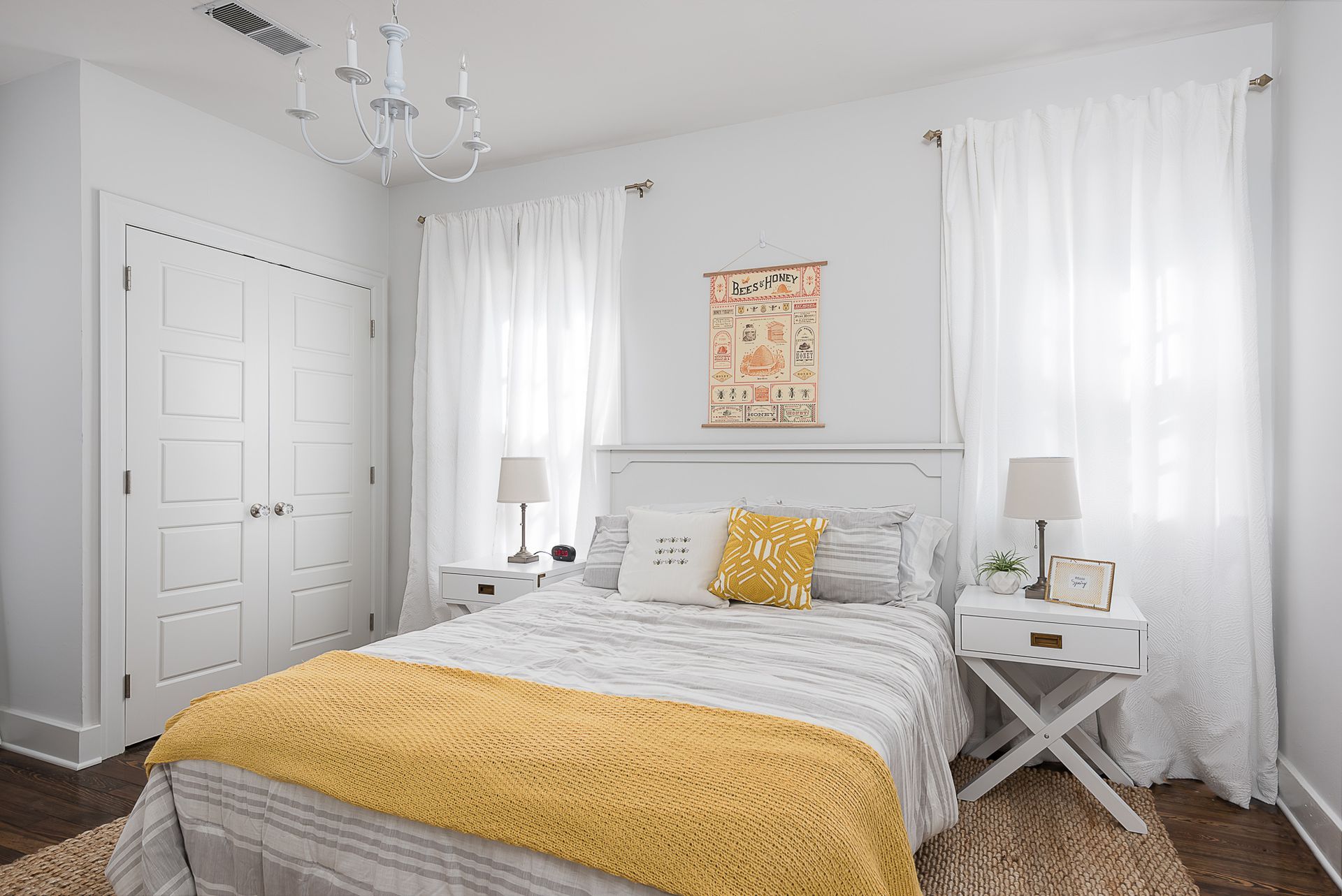 A bedroom with a bed , nightstands , and a chandelier.