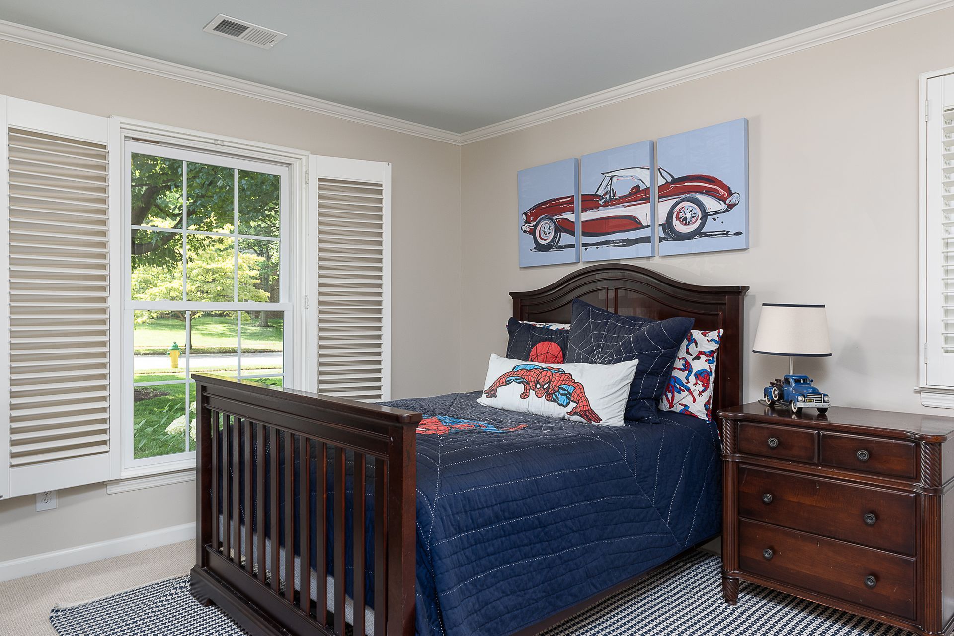 A bedroom with a bed , dresser , nightstand , and window.