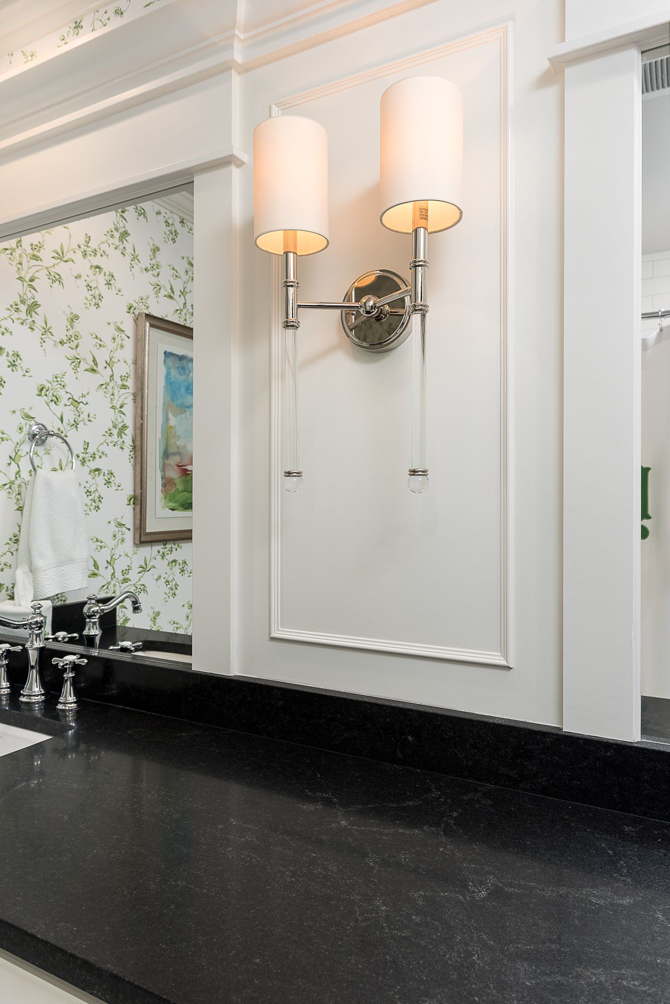 A bathroom with a black counter top and two lights on the wall