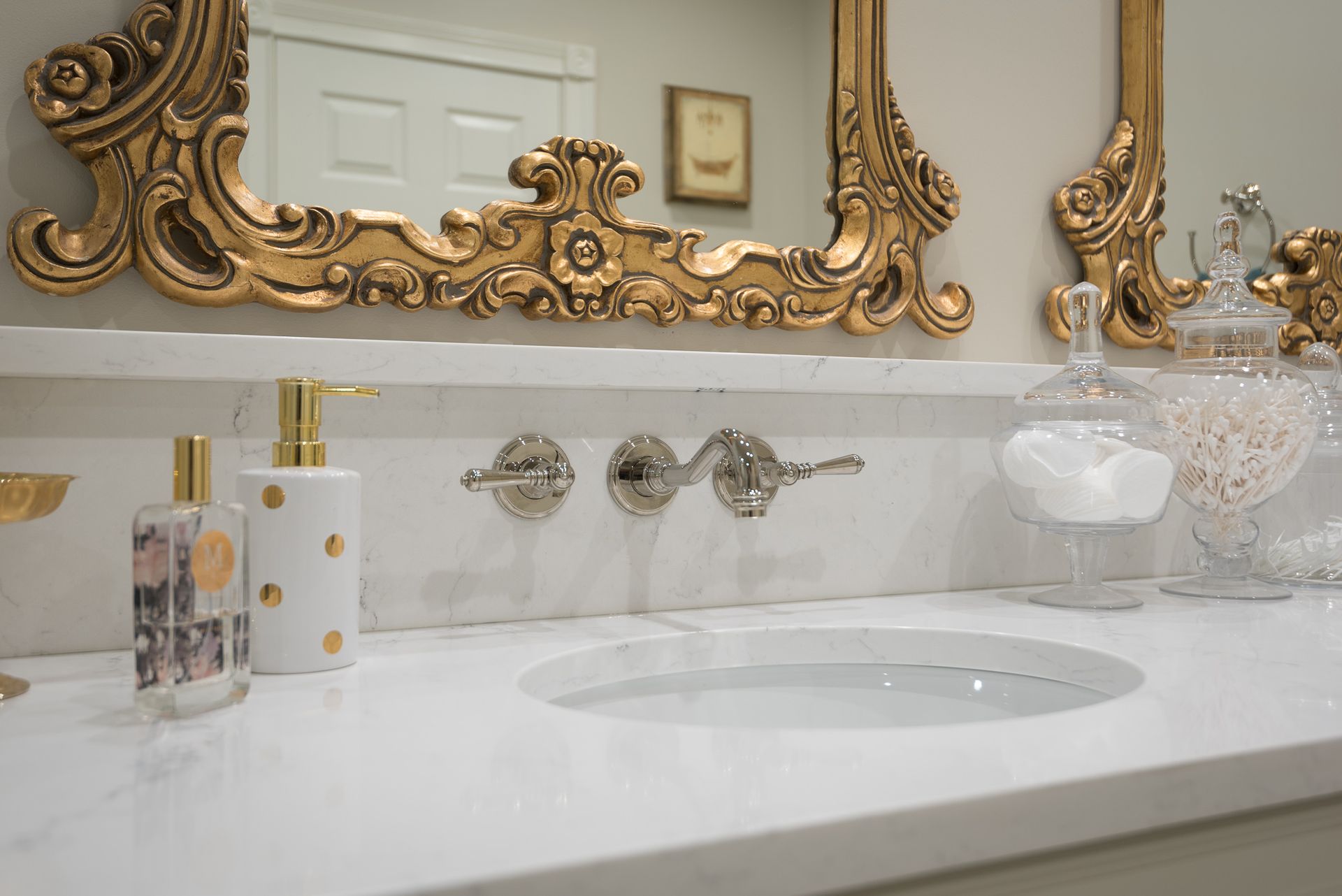 A bathroom with a sink , mirror and soap dispenser.