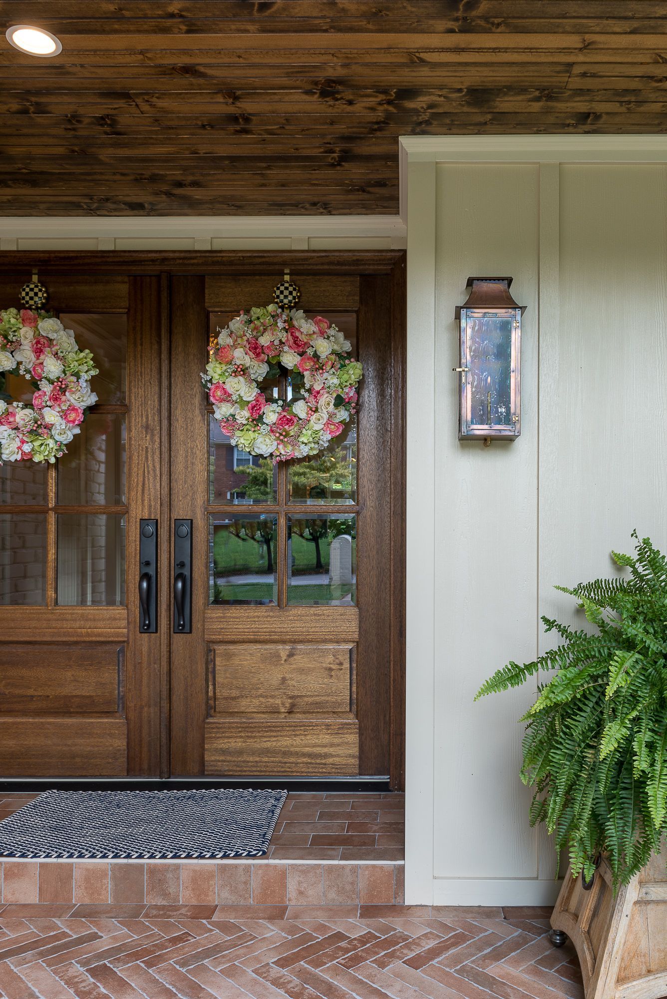 The front door of a house with two wreaths on it.