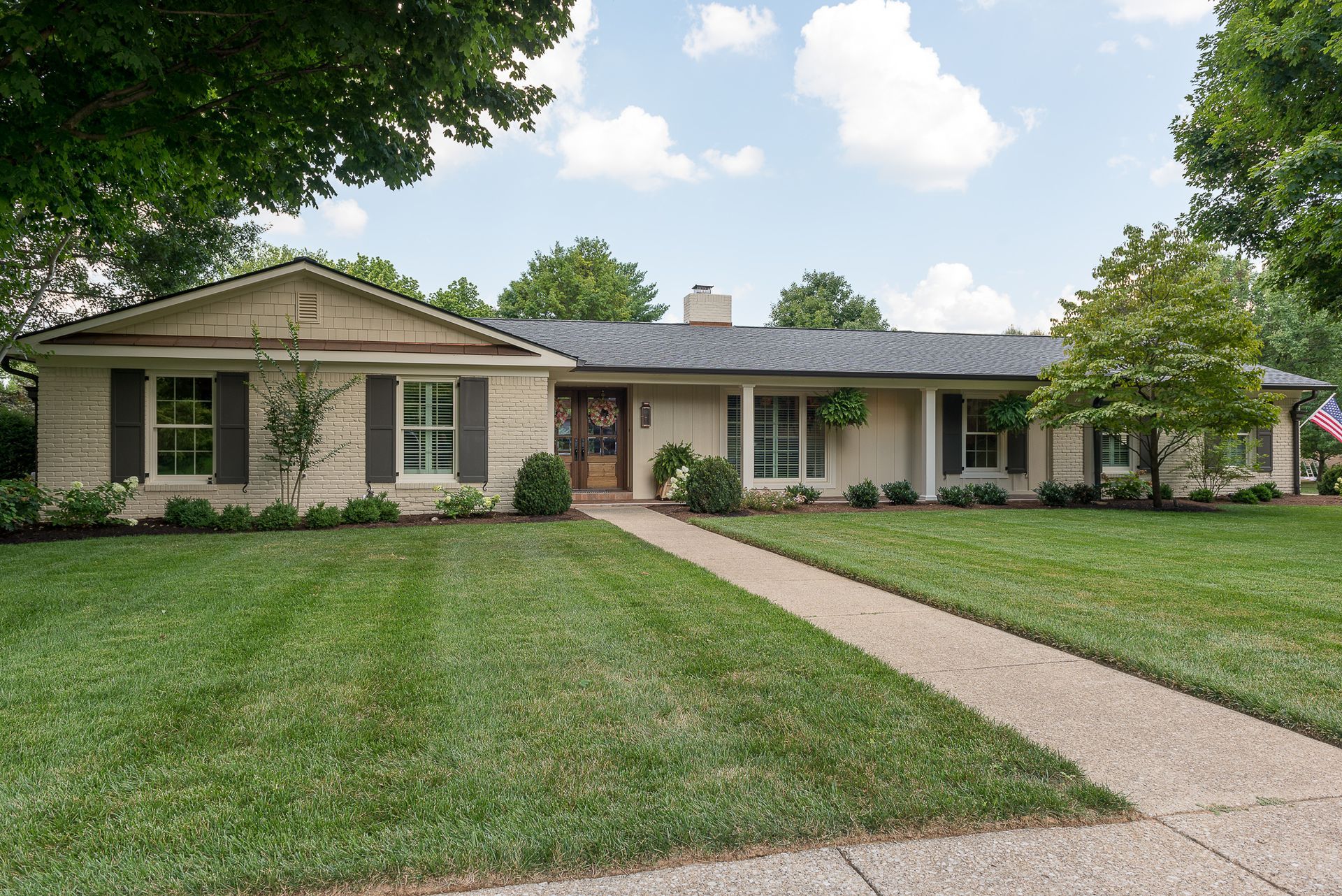 A house with a lush green lawn and a walkway leading to it