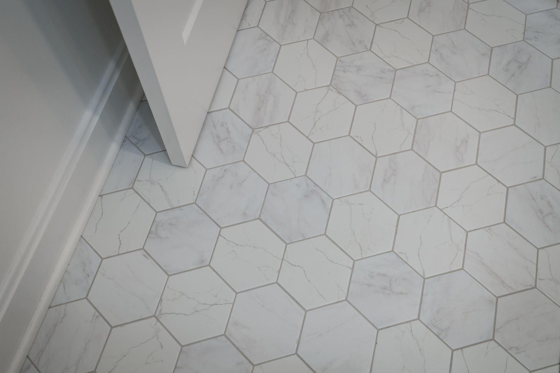 A close up of a white tile floor with a hexagon pattern.
