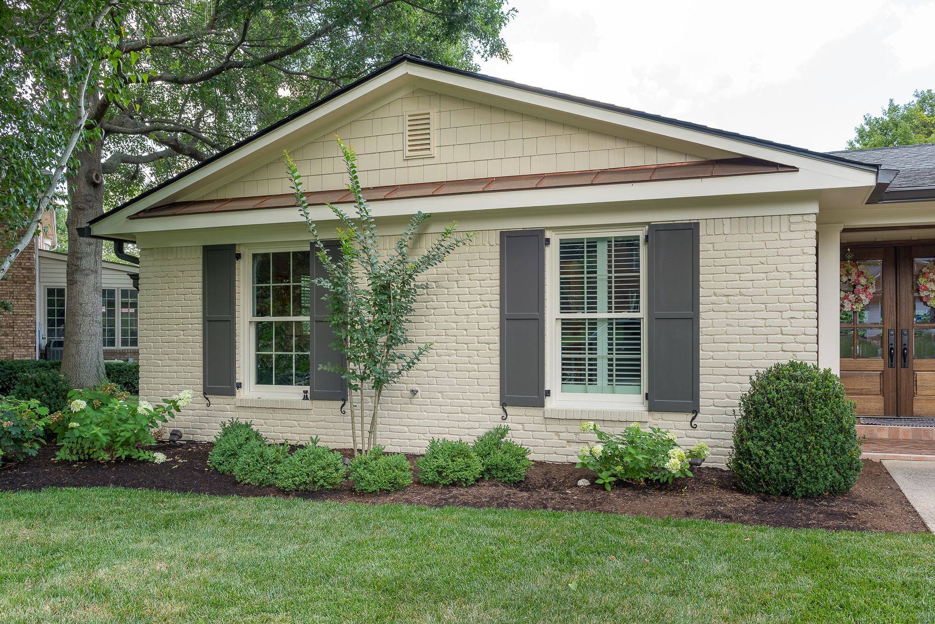 A white brick house with black shutters on the windows