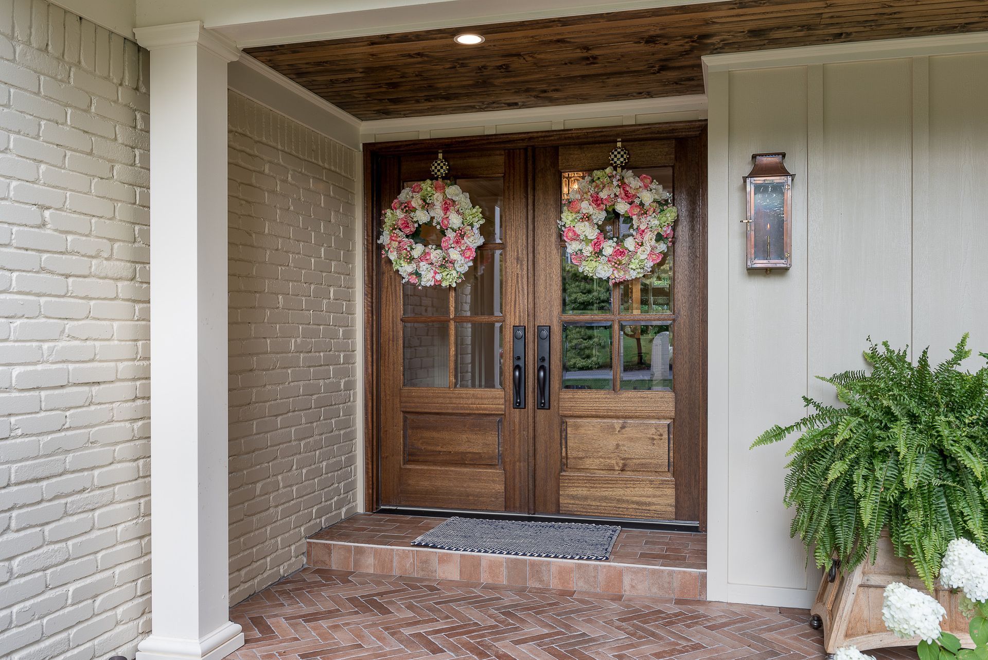 The front door of a house with two wreaths hanging from it.