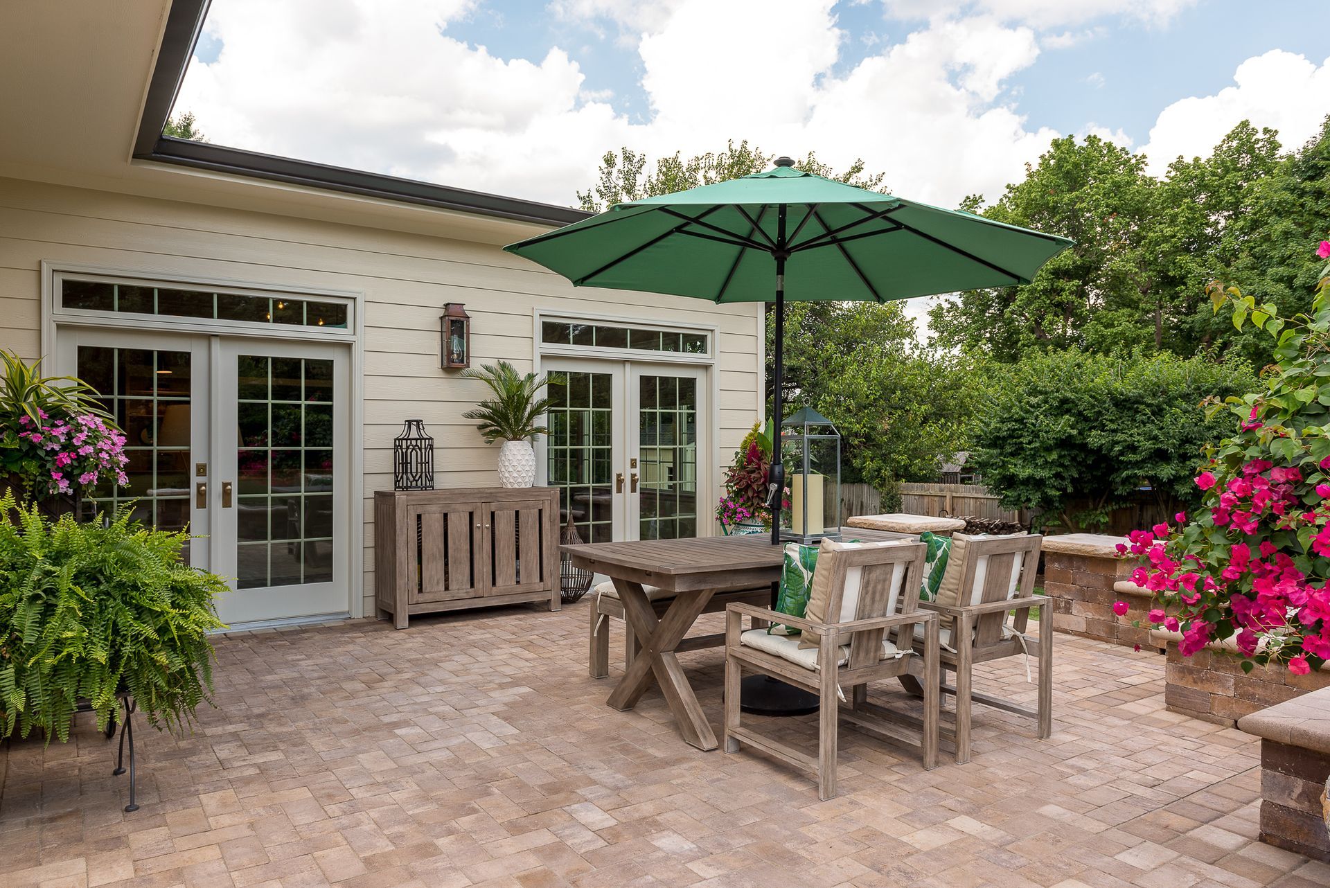 A patio with a table and chairs and a green umbrella.