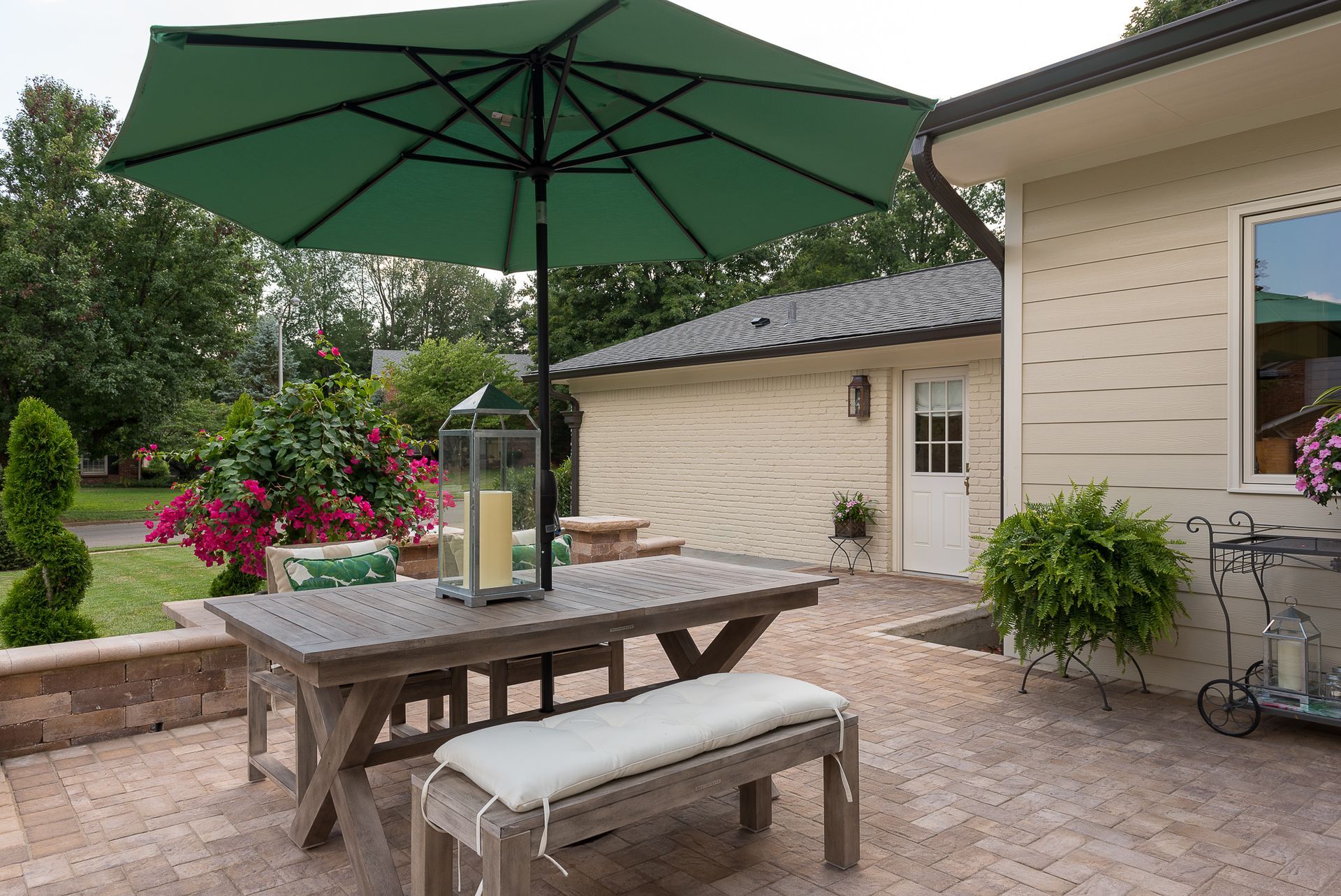 A patio with a table and benches under an umbrella