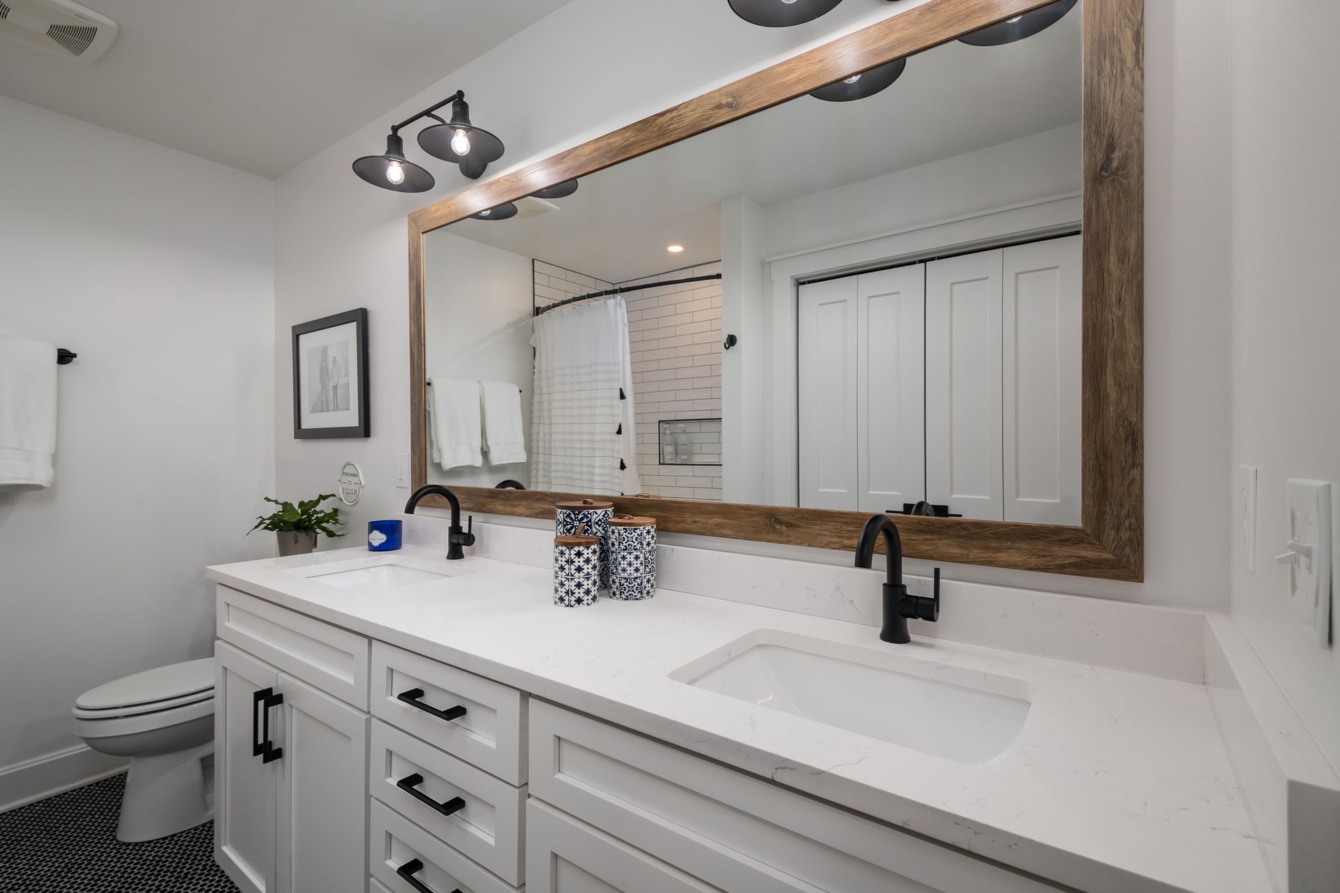 A bathroom with two sinks , a toilet , and a large mirror.
