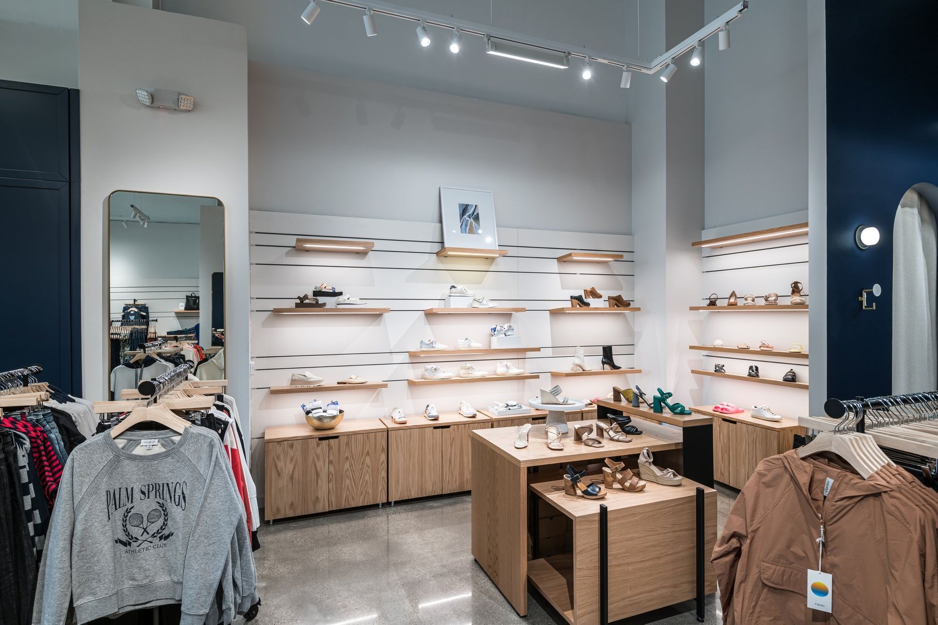 A clothing store with a lot of shelves and clothes hanging on racks.