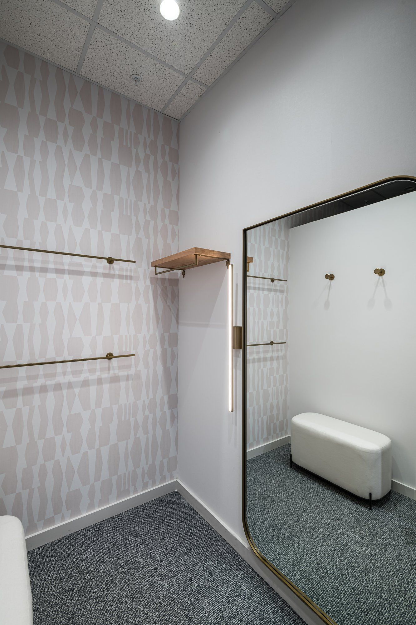 A dressing room with a large mirror and a bench.