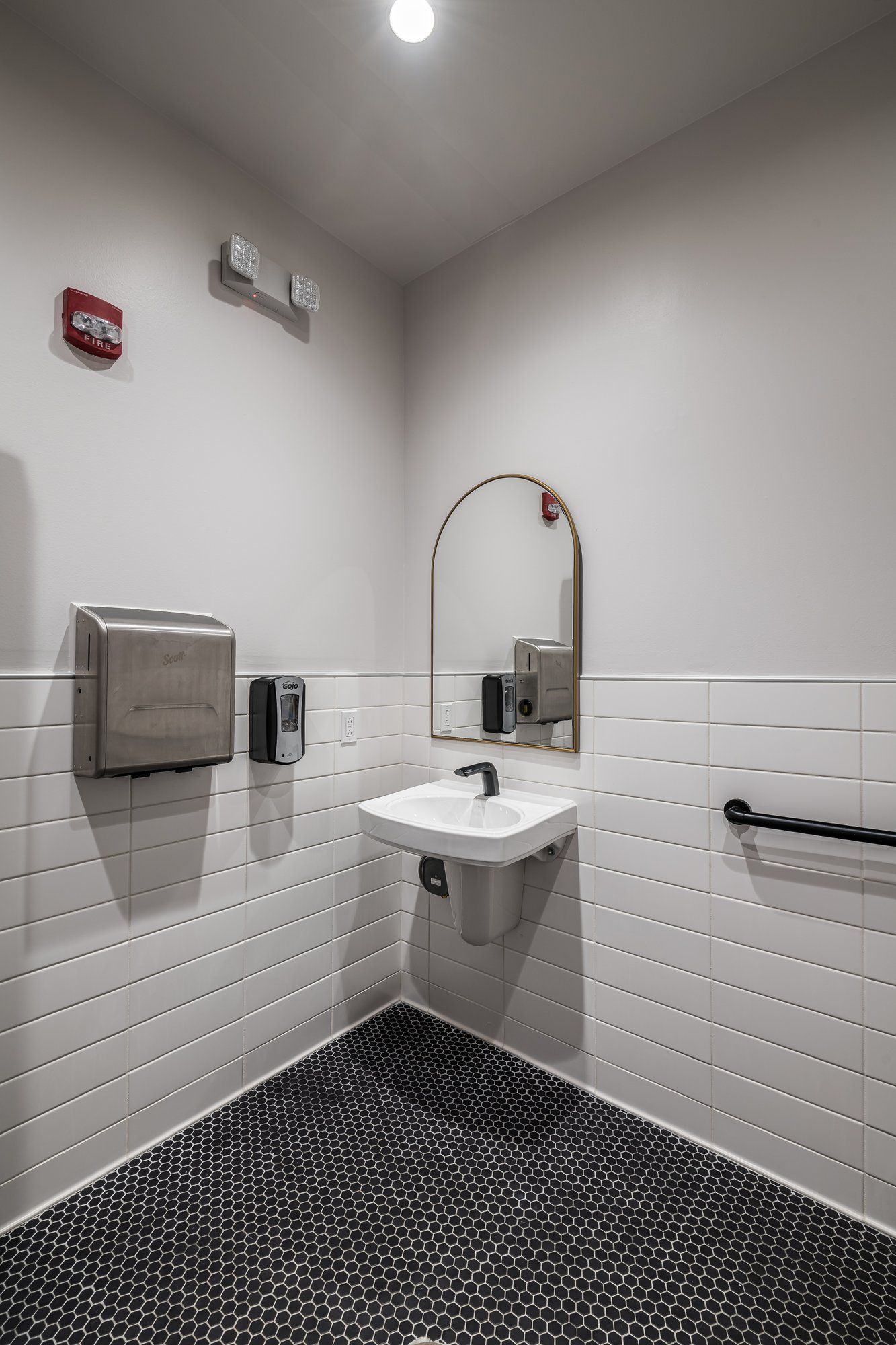A bathroom with a sink , mirror and handrails.