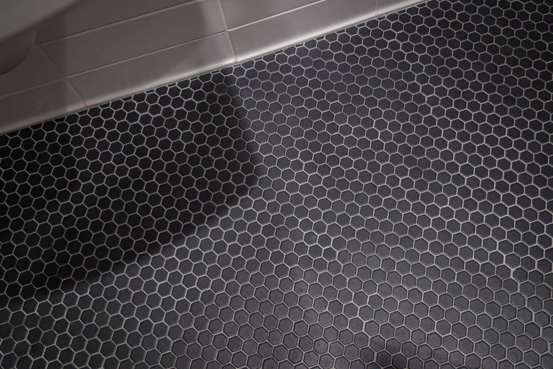 A close up of a black tile floor with a honeycomb pattern.
