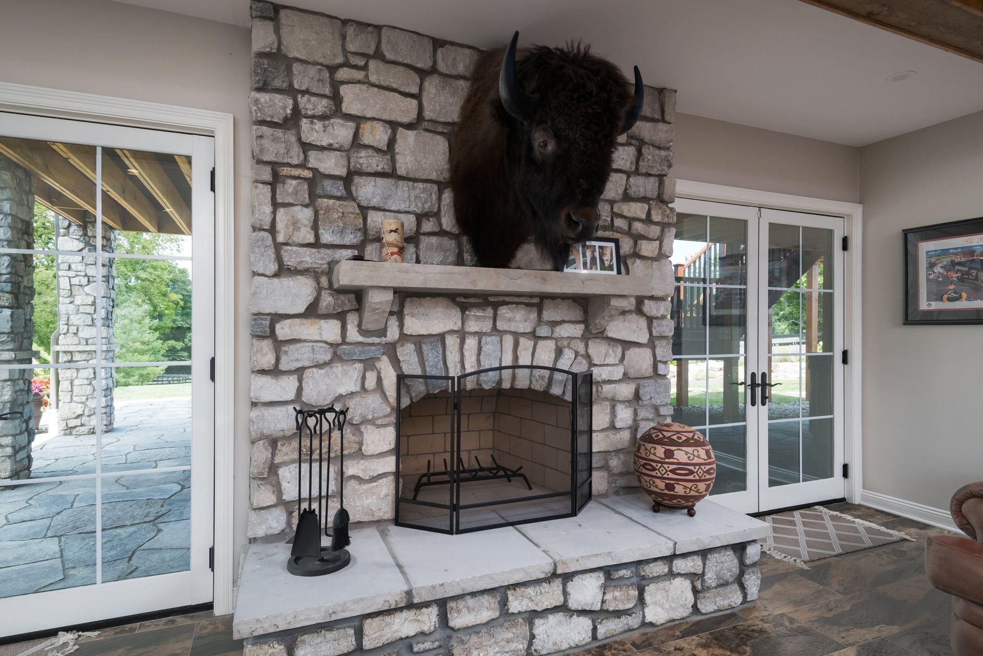 A stone fireplace with a stuffed buffalo on the mantle.
